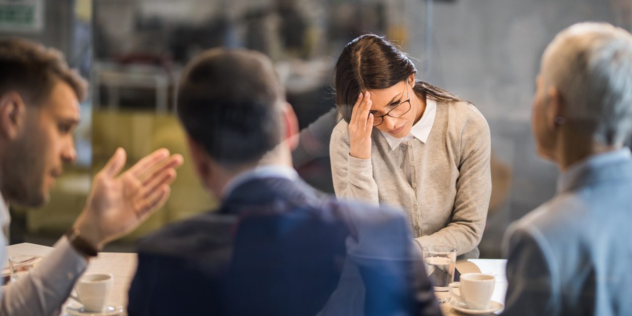 Young frustrated woman failed on a job interview in the office. Young woman feeling disappointed after failing on a job interview in the office. The view is through glass.