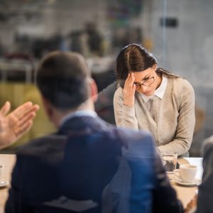 Young frustrated woman failed on a job interview in the office. Young woman feeling disappointed after failing on a job interview in the office. The view is through glass.