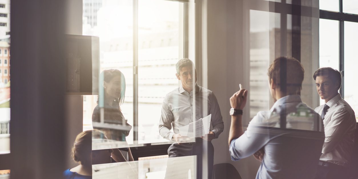 Business people having discussion in board room A photo of business people having discussion in board room. Male and female professionals are seen through glass. They are working in office.